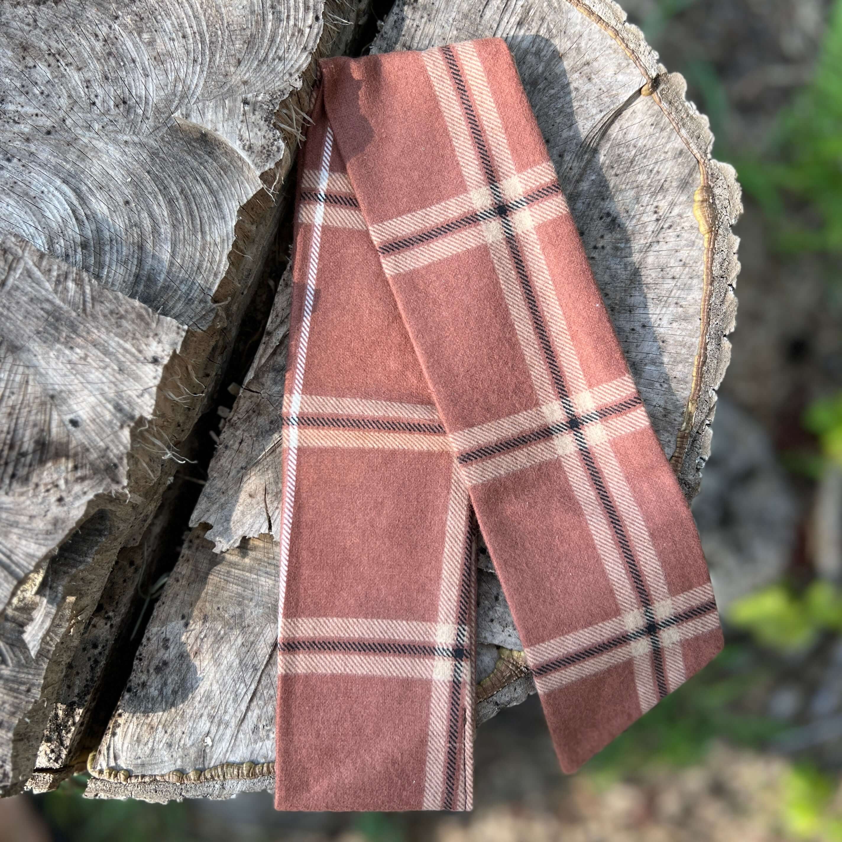 Plaid scarf on a wooden log with a natural background