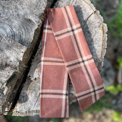 Plaid scarf on a wooden log with a natural background