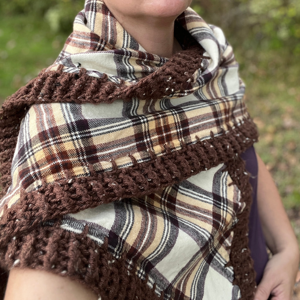 Plaid shawl with brown crochet border worn by a person outdoors