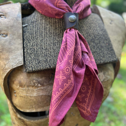A burgundy bandana with a tan geometric pattern tied around dress form