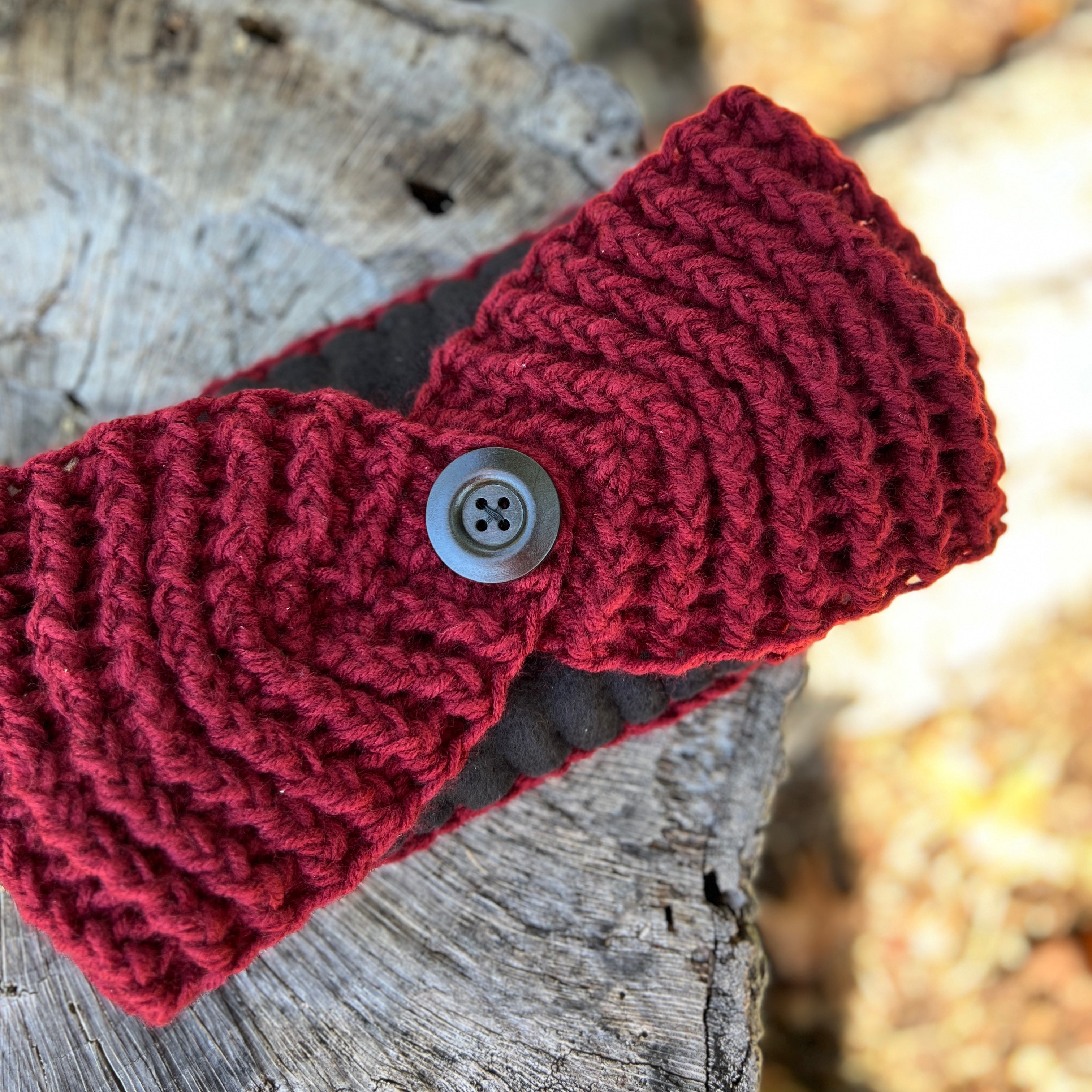 winter headband in Red with a button on a wooden surface