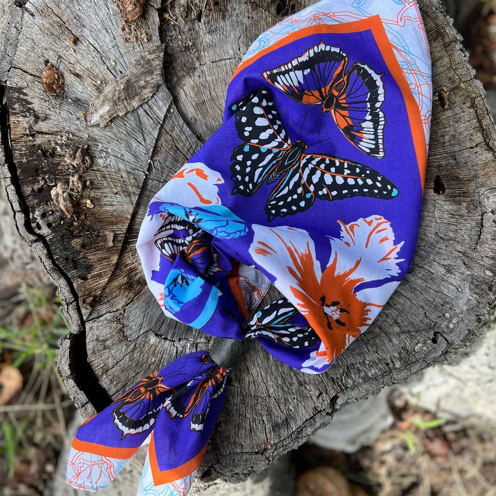 Colorful butterfly-patterned headscarf on a wooden log