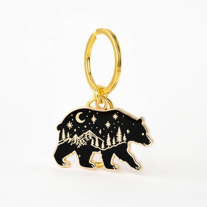 Gold keychain with a bear charm featuring mountain and star design on a white background