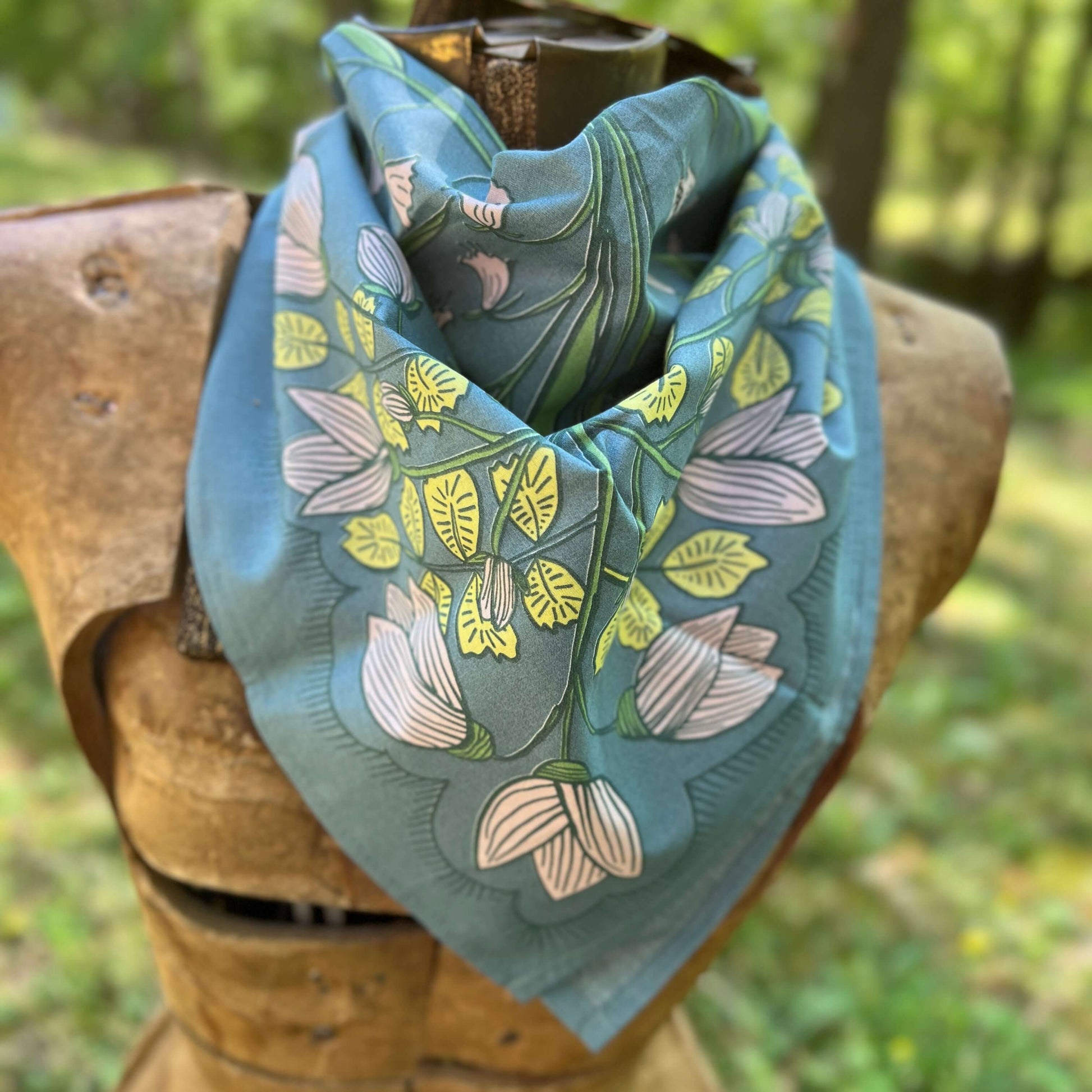 Floral patterned bandana on a wooden mannequin with a natural background
