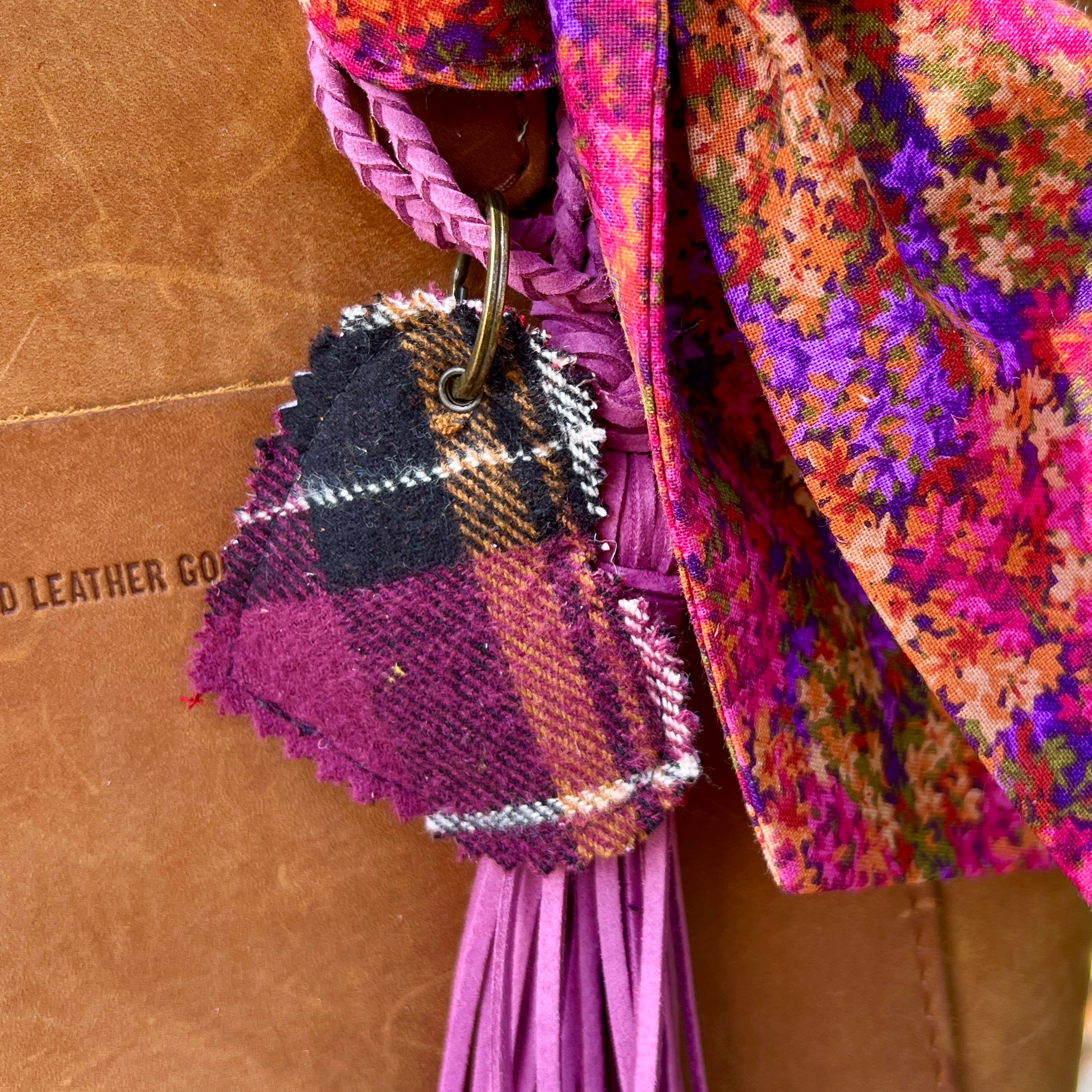 Colorful textured keychain attached to a multicolored fabric bag on a brown leather background.