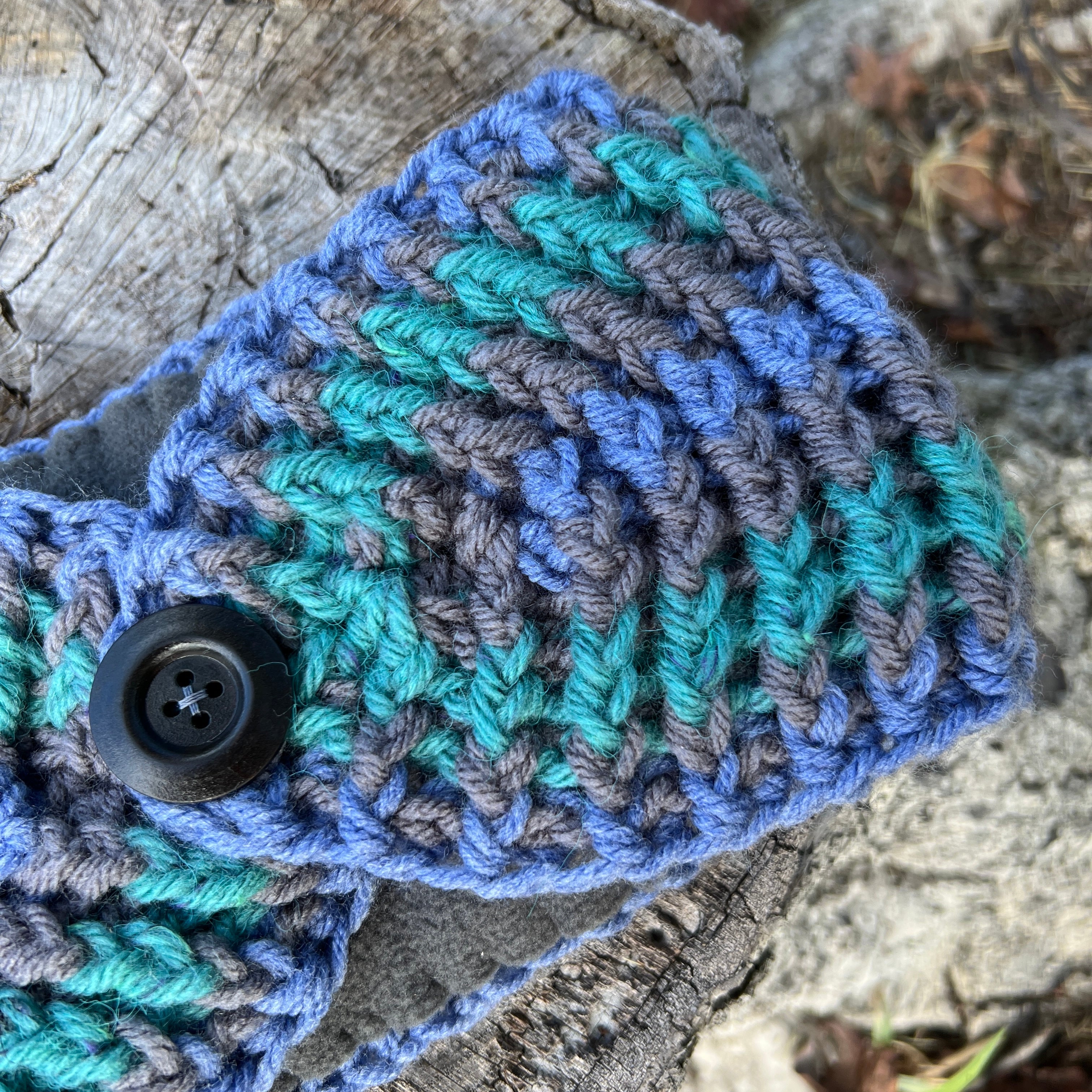 Crocheted item with a button on a wooden surface