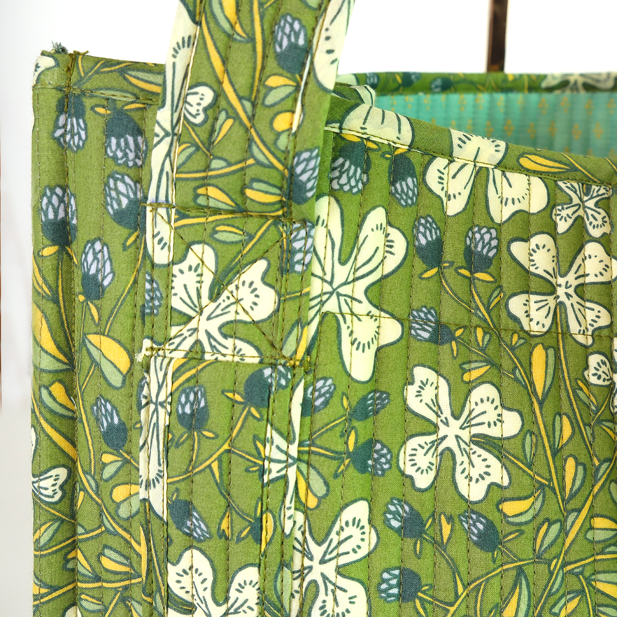 Green floral patterned fabric with white flowers and blue accents