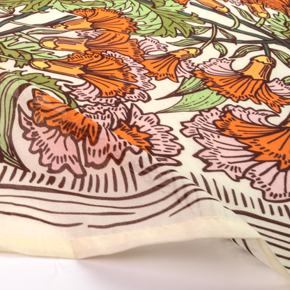 A close-up of a printed textile or scarf with a botanical pattern featuring orange flowers, pink and green leaves, and brown linework on an off-white background.