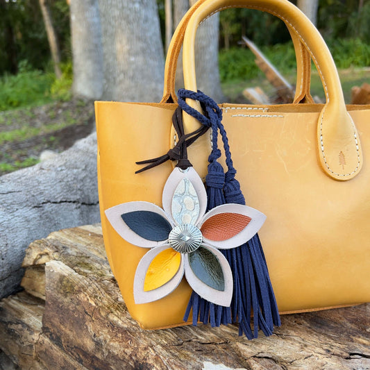 leather flower purse charm in earthy colors shown with navy tassel