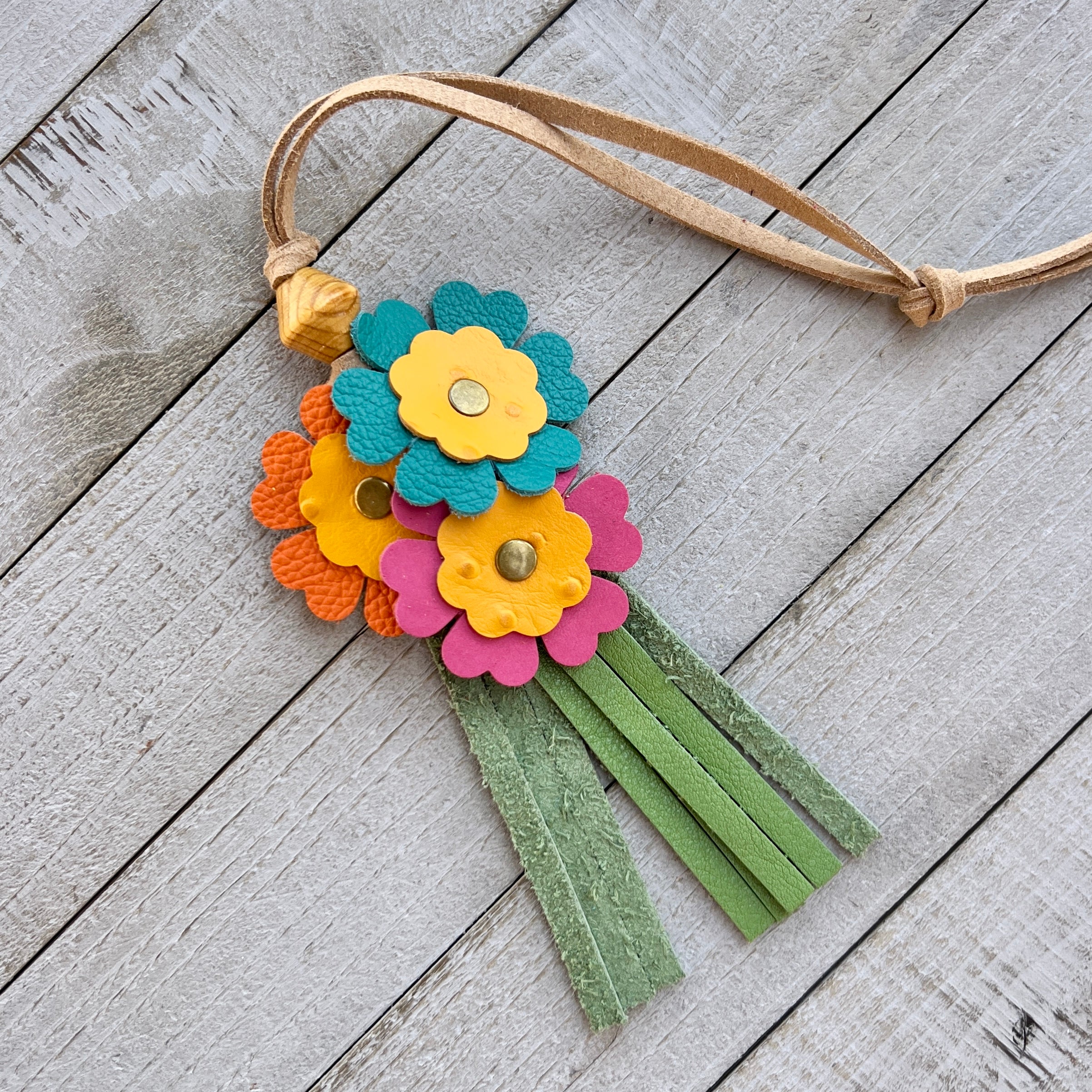 Colorful flower-shaped keychain with tassels on a wooden surface
