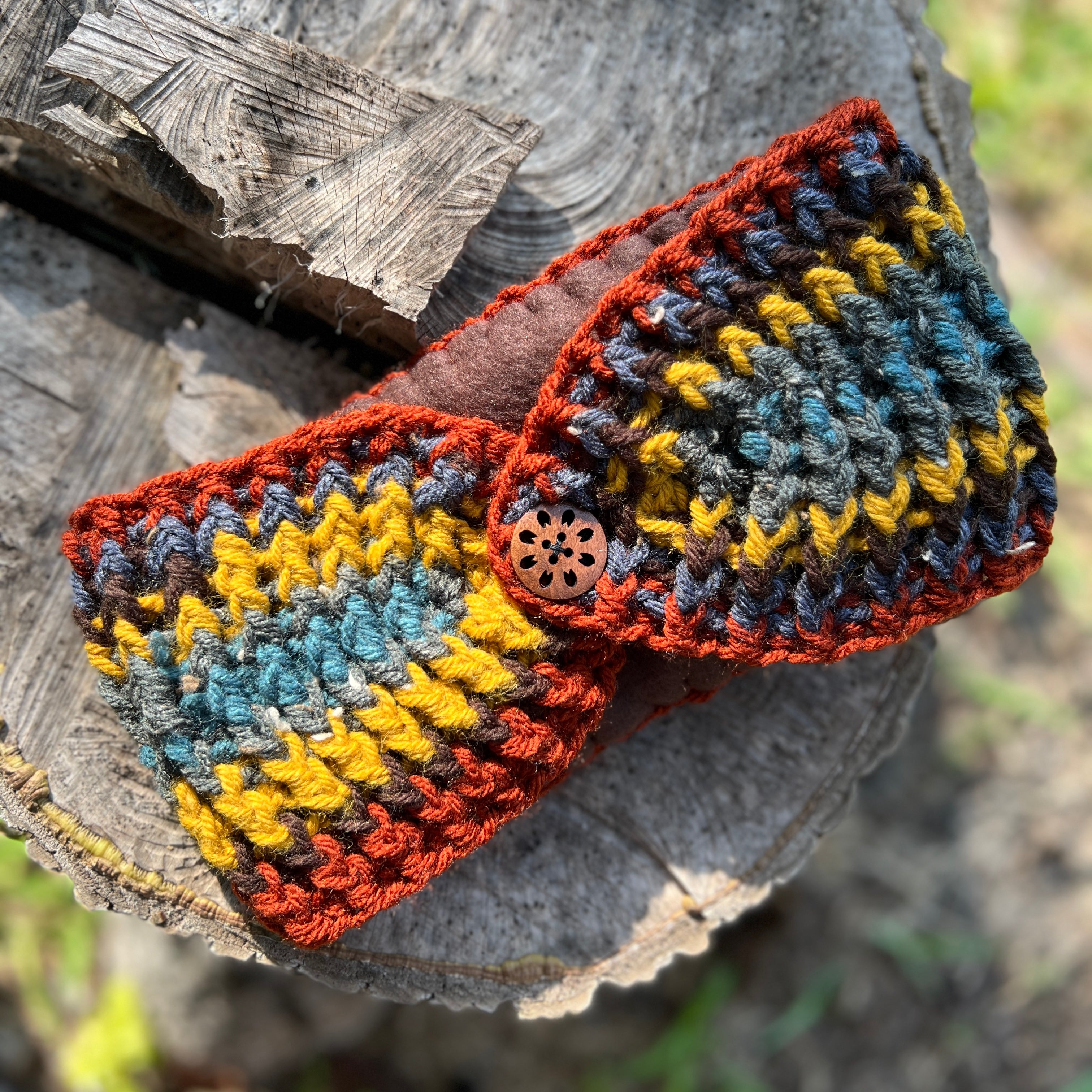 Colorful crocheted headband with a button on a wooden surface