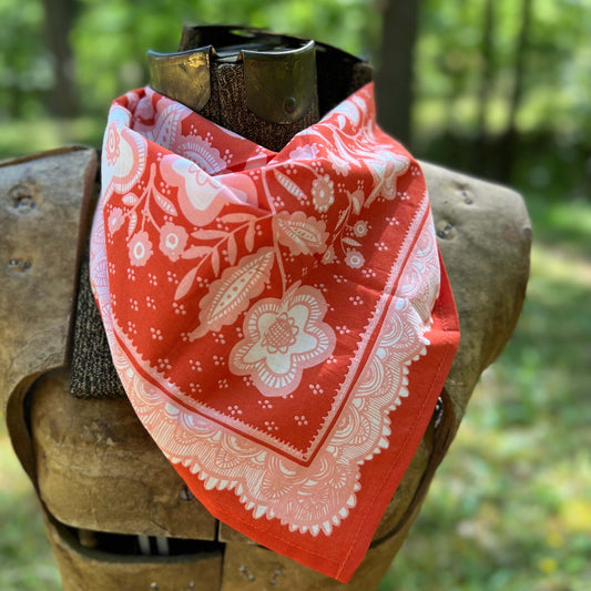 Red bandana with white floral patterns on a wooden surface outdoors.