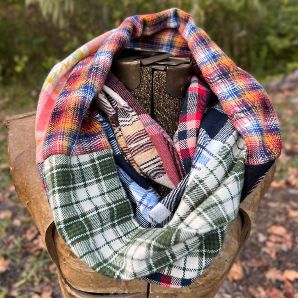 Plaid infinity scarf on a wooden block with a natural outdoor background