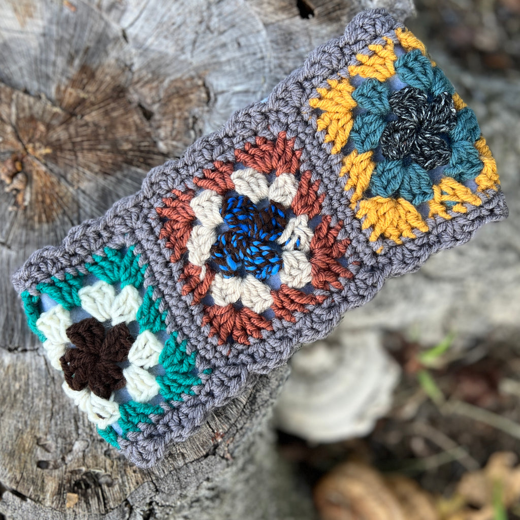Crocheted headband with colorful flower patterns on a wooden surface