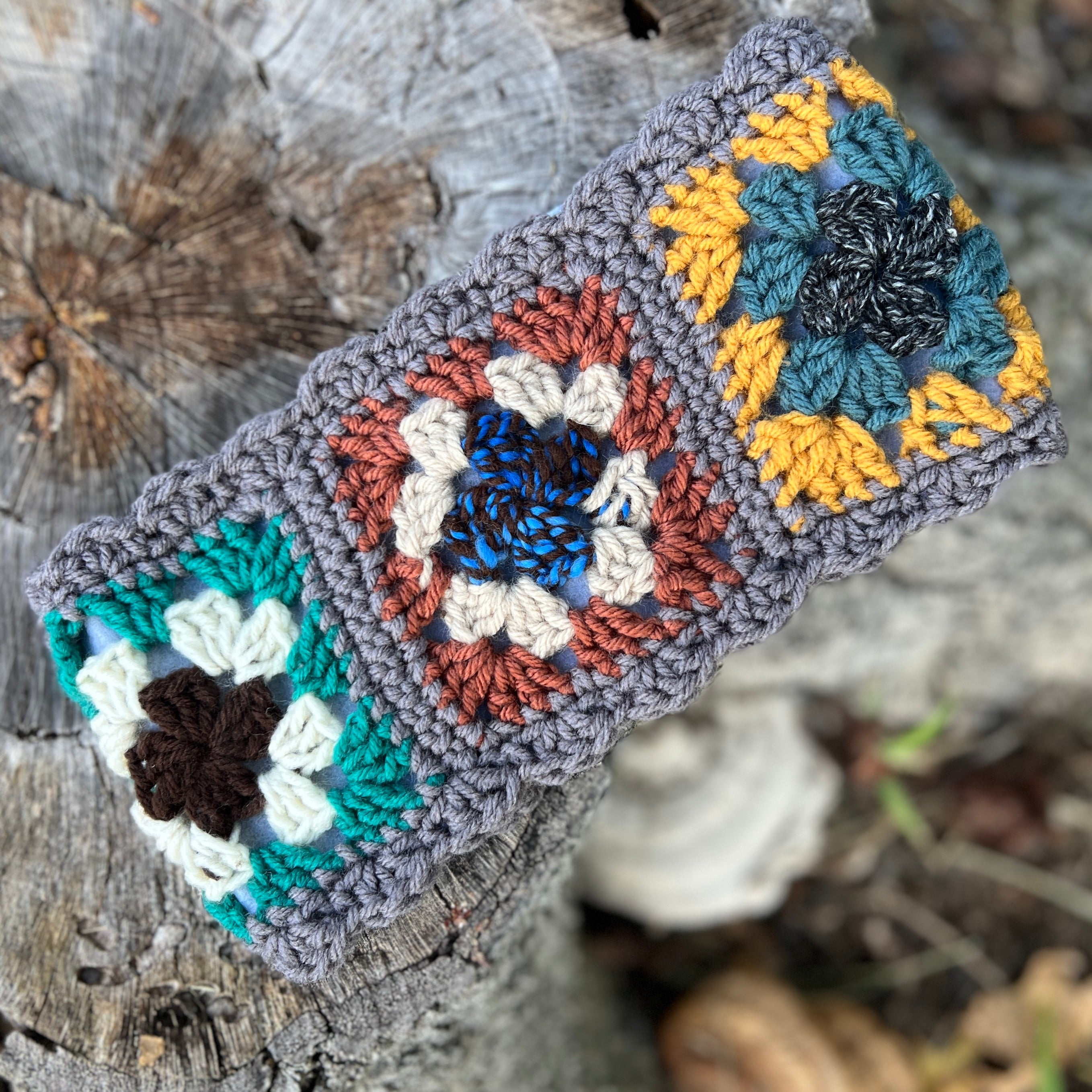 Crocheted headband with colorful flower patterns on a wooden surface