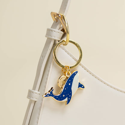 Keychain with a blue whale charm on a white strap against a beige background
