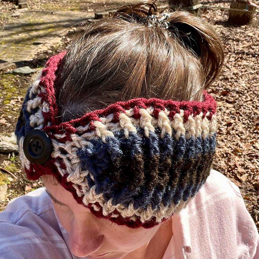 Person wearing a crocheted headband with red, white, and blue colors in an outdoor setting.