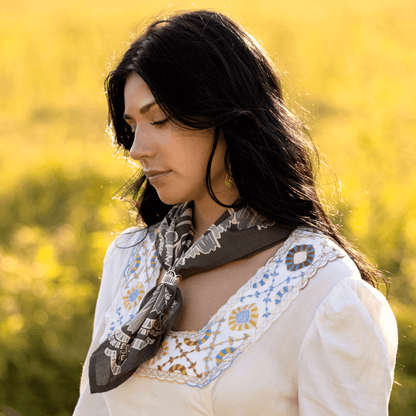 Woman wearing a white blouse with embroidery, standing in a field of yellow flowers.