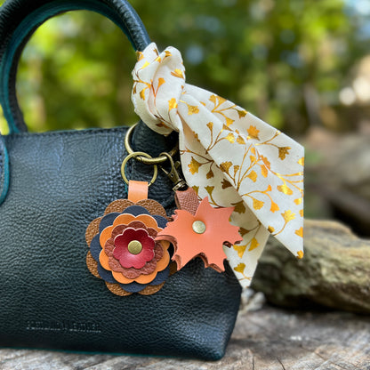 layered leather flower with orange leaf charm. Shown on blue handbag with orange metallic leaf scarf on handle
