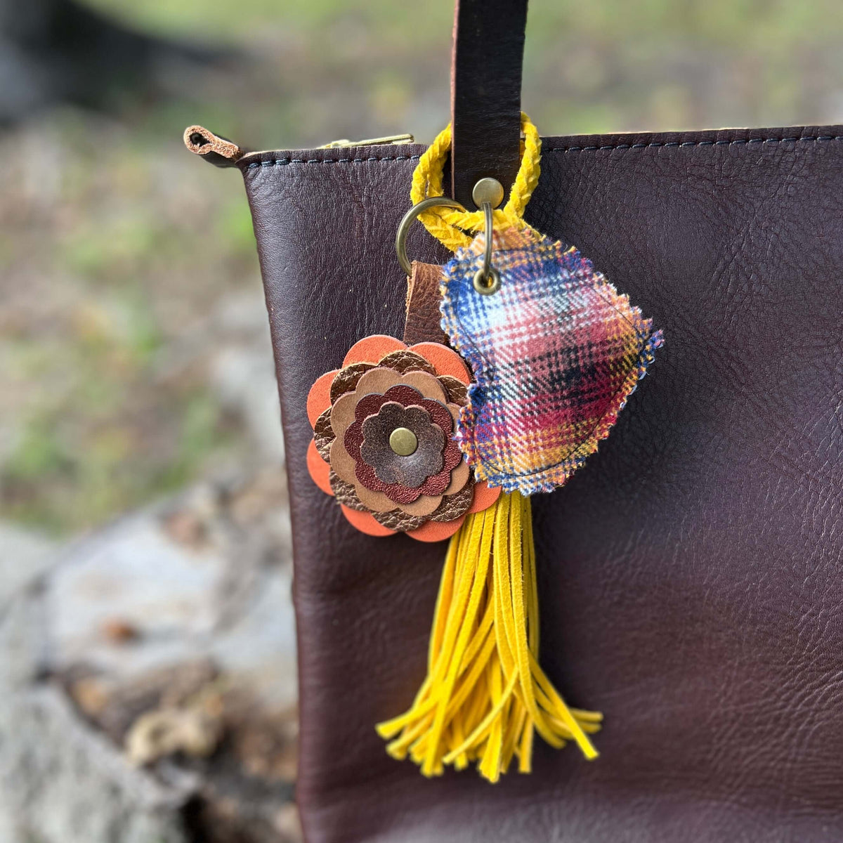 Decorative keychain with colorful tassel attached to a brown leather bag.