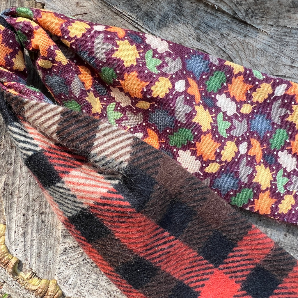 Two fabric swatches with autumn leaf pattern and plaid design on a wooden surface.