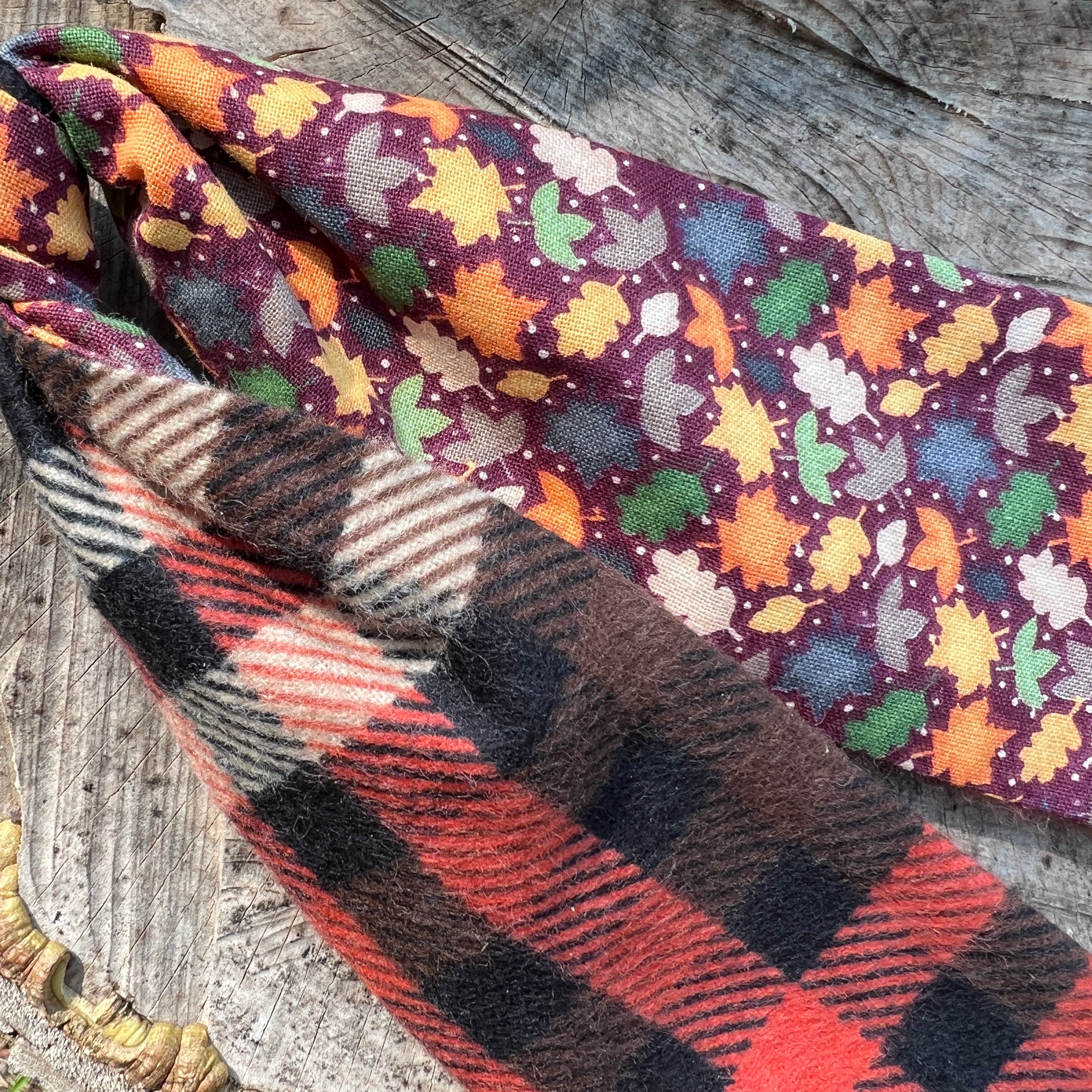 Two fabric swatches with autumn leaf pattern and plaid design on a wooden surface.