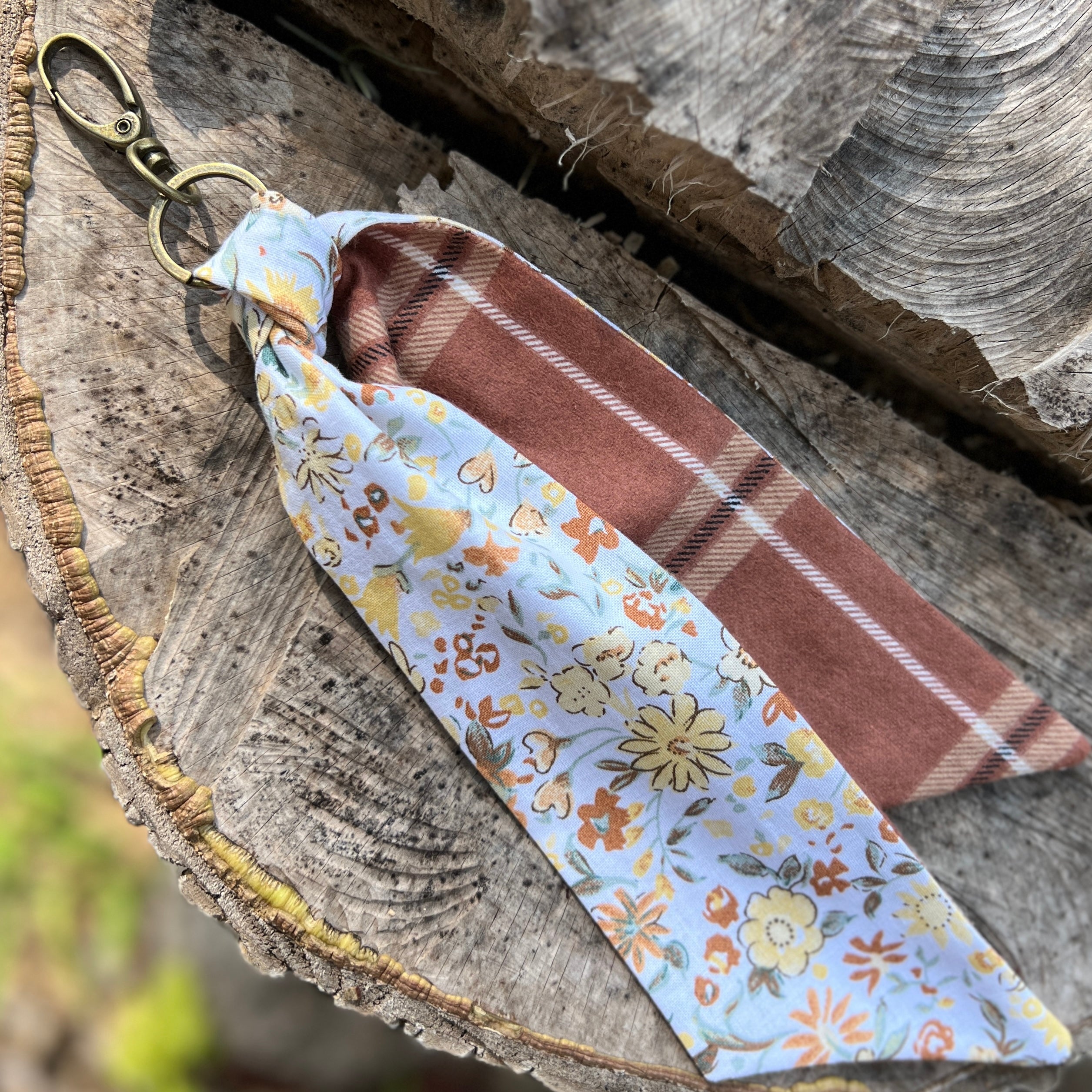Keychain with floral and plaid fabric strip on a wooden surface