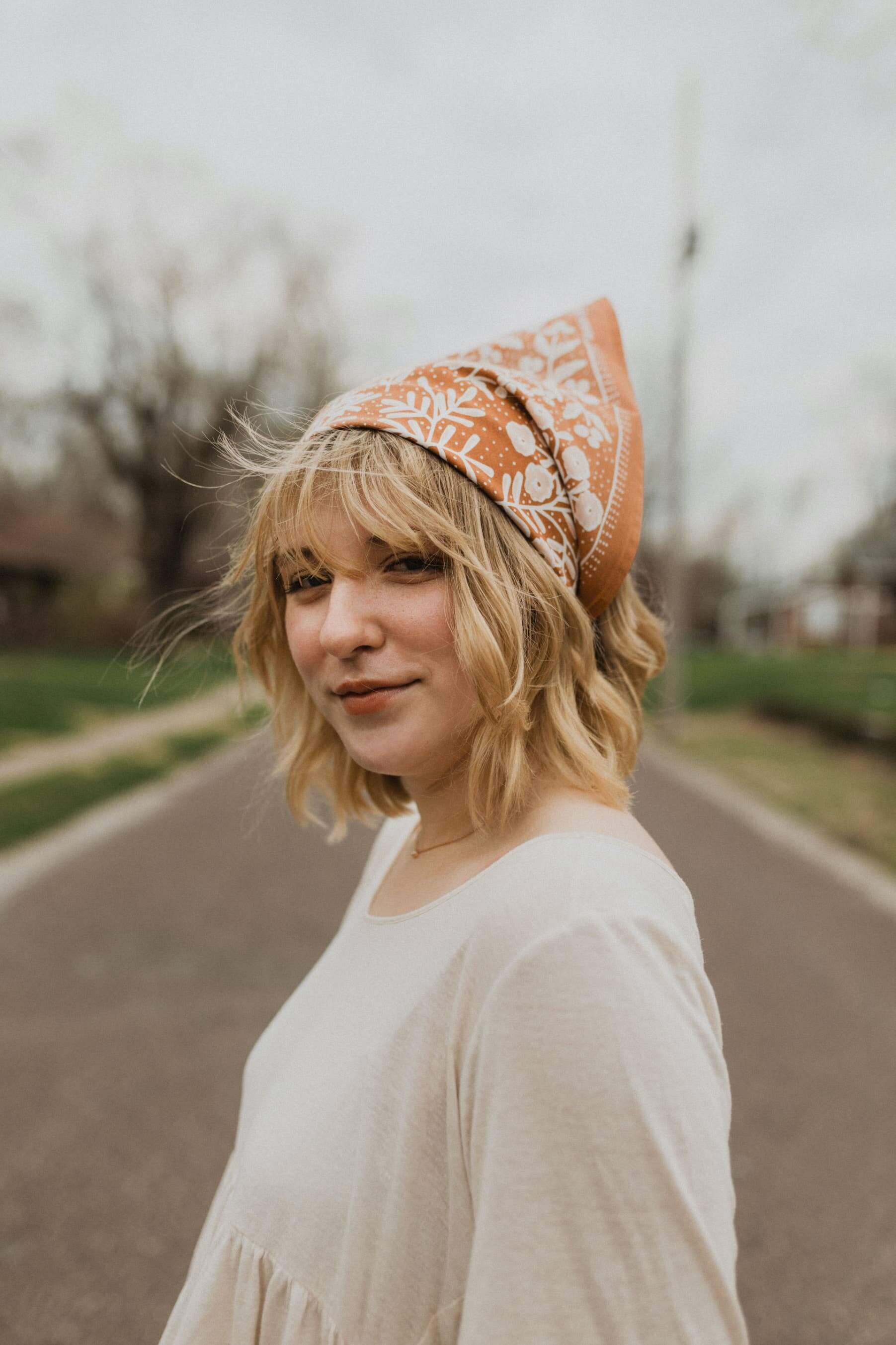 Woman wearing a patterned headscarf outdoors on a road