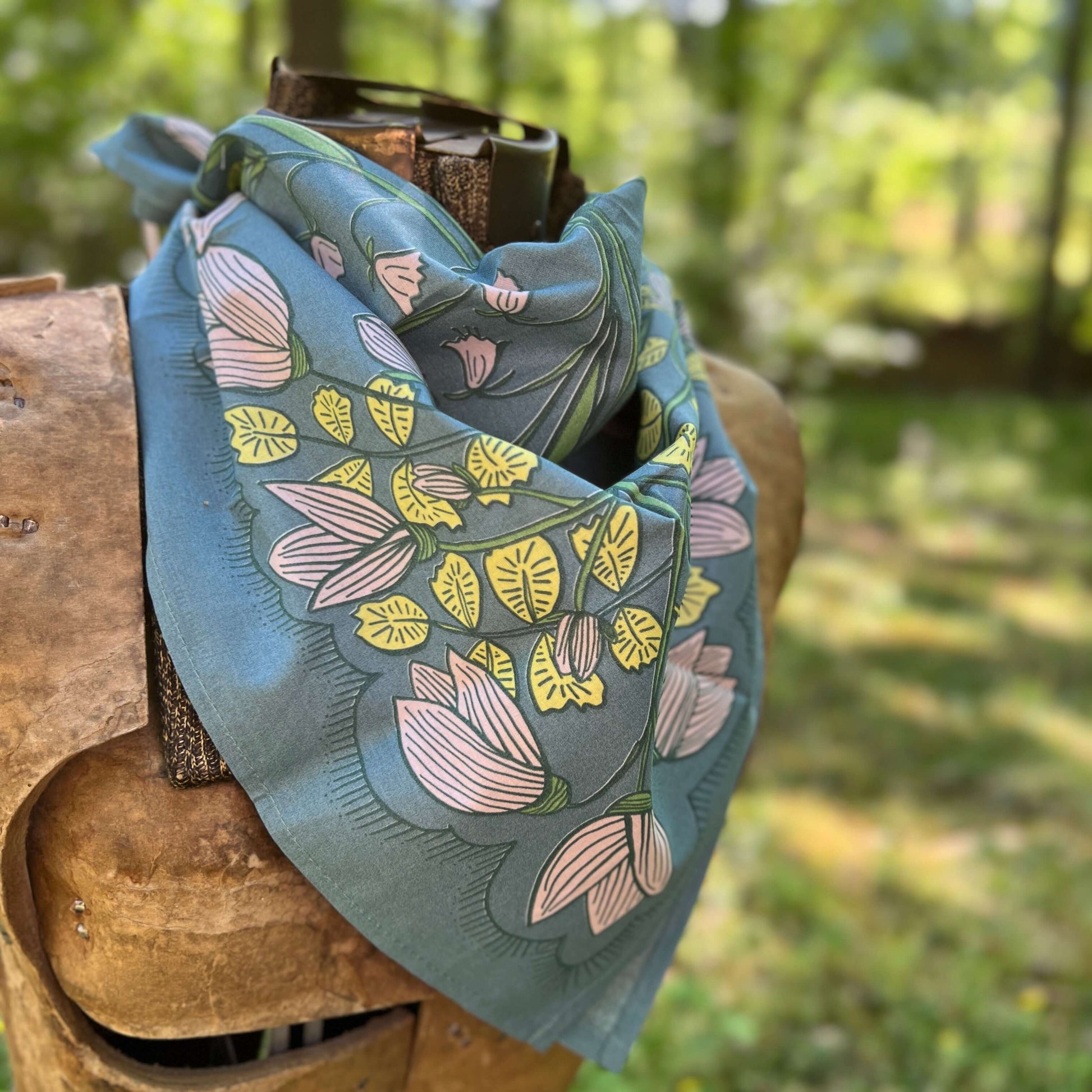 Floral patterned scarf on a wooden bench with a natural background