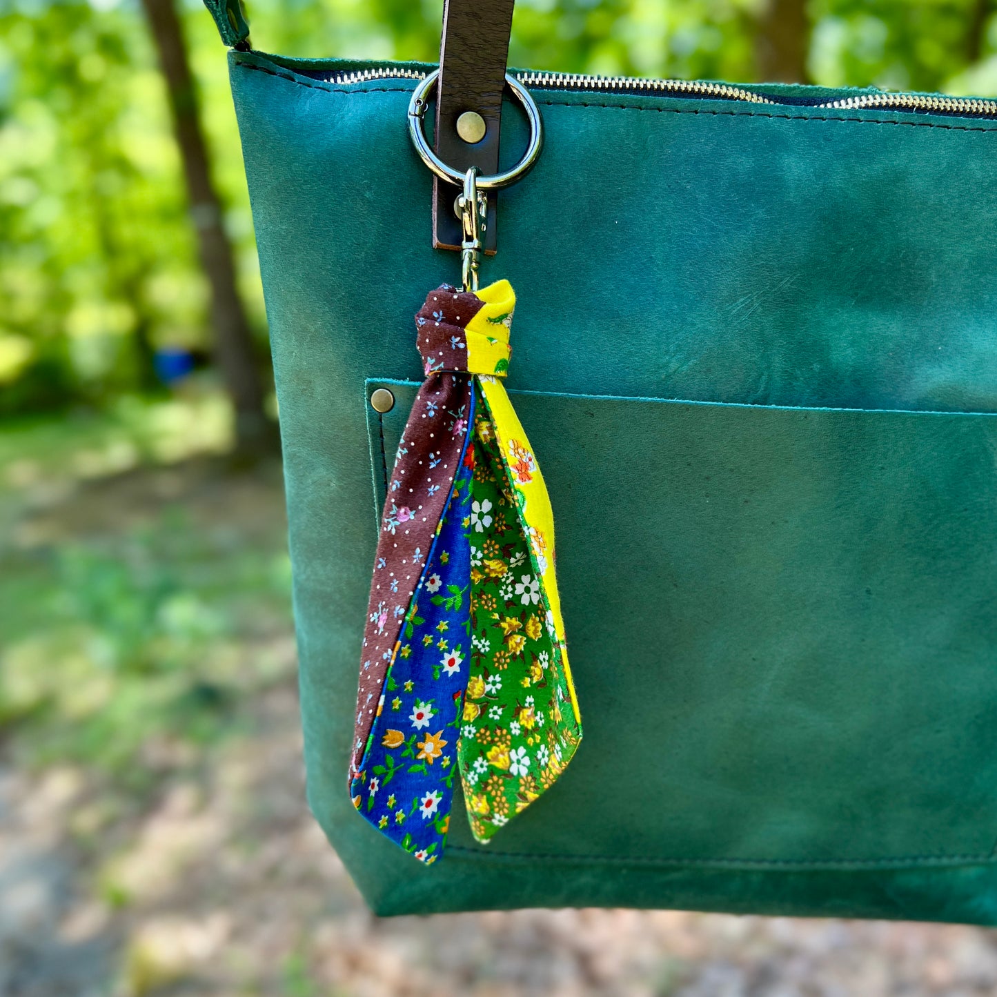 Green bag with colorful fabric keychains hanging from a keyring.