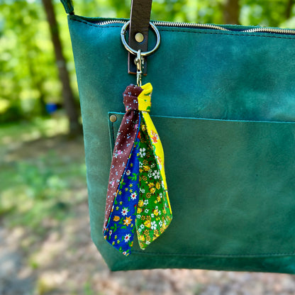 Green bag with colorful fabric keychains hanging from a keyring.
