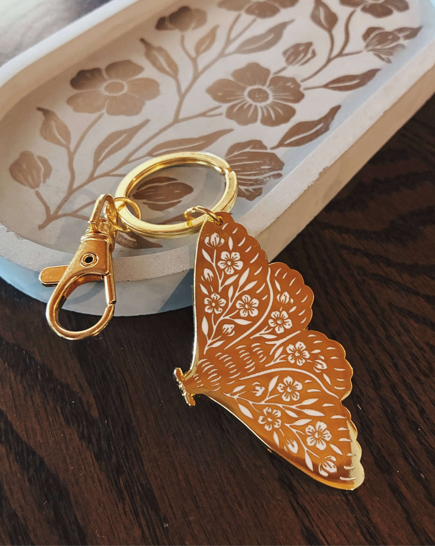 Butterfly-shaped keychain with floral design on a wooden surface