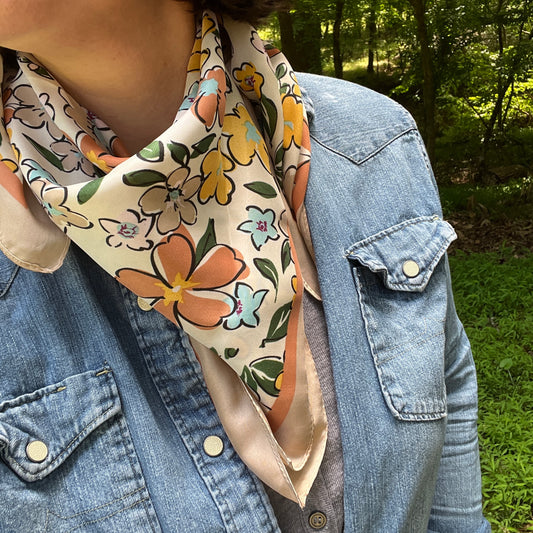 Person wearing a floral scarf with a denim jacket in a natural setting