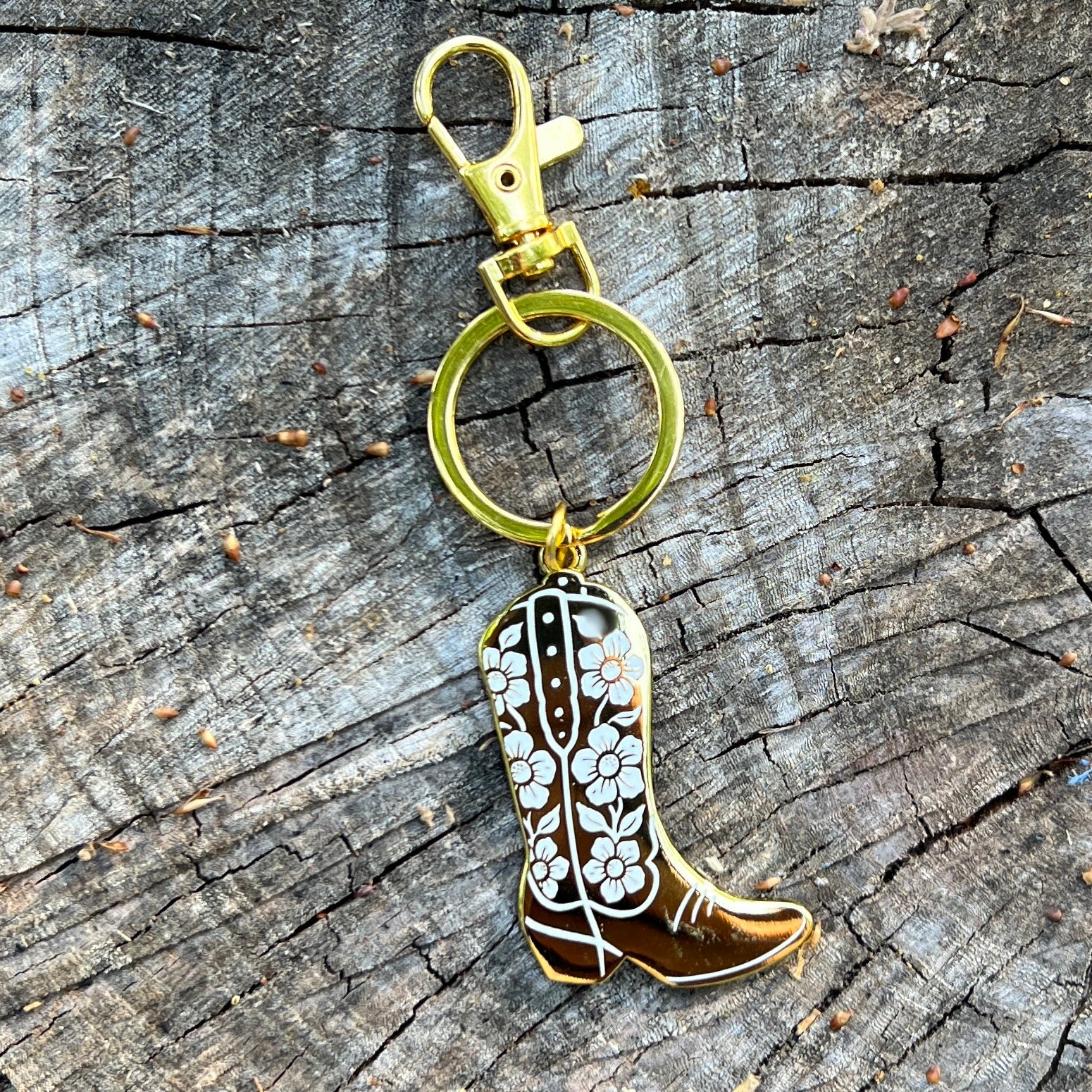Cowboy boot keychain with floral design on a wooden surface