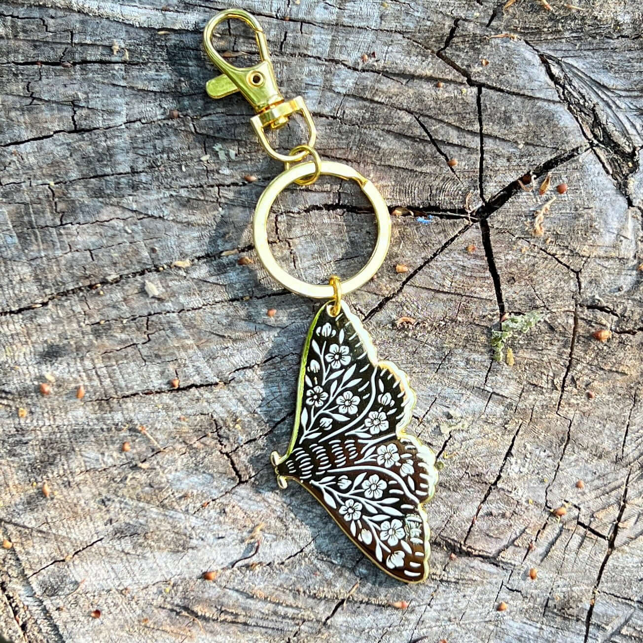 Butterfly-shaped keychain with floral design on a wooden surface