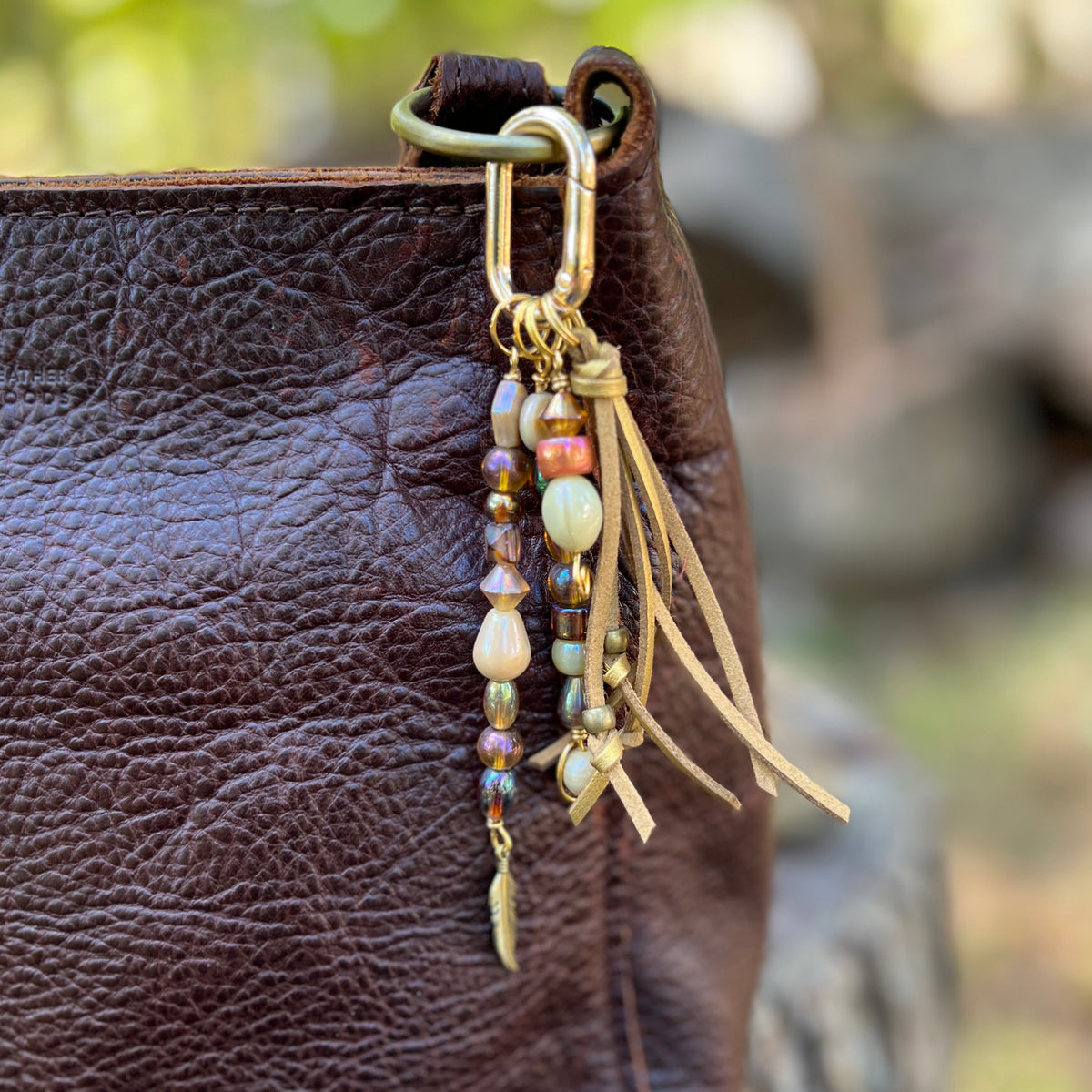 gold glass beaded bag charm with tassel and feather charm