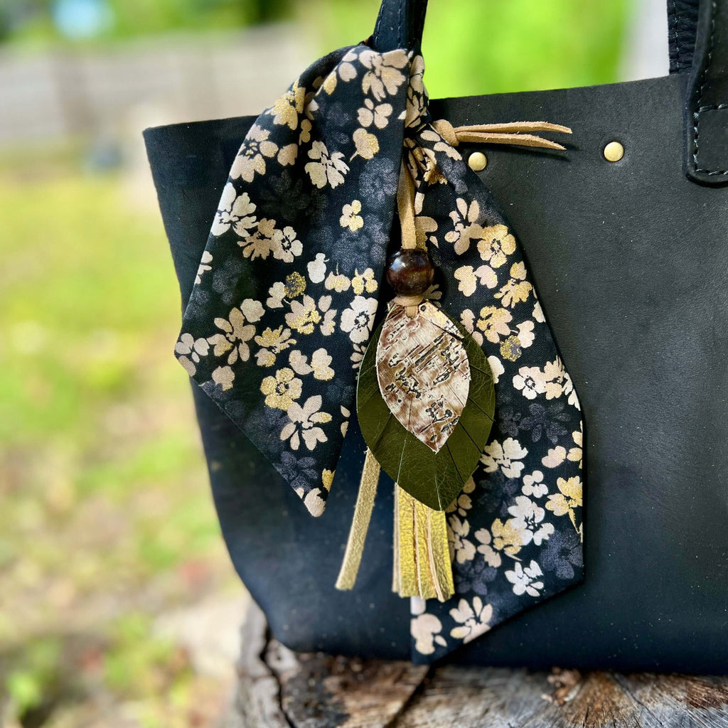 black and gold scarf with leather charm on black bag