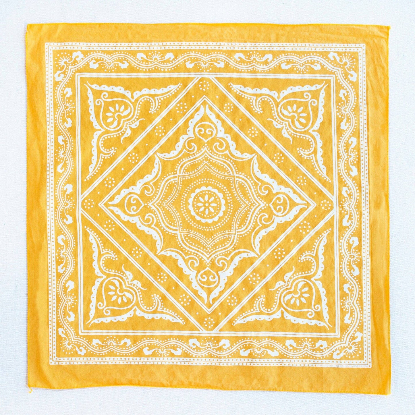 Yellow bandana with white intricate patterns on a white background