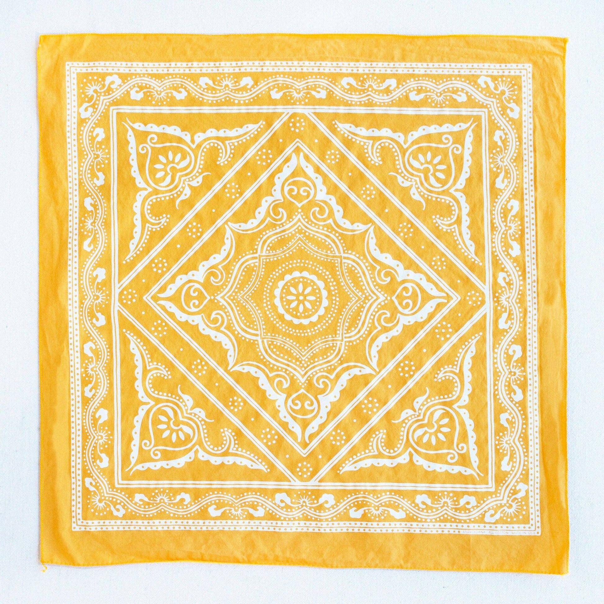 Yellow bandana with white intricate patterns on a white background