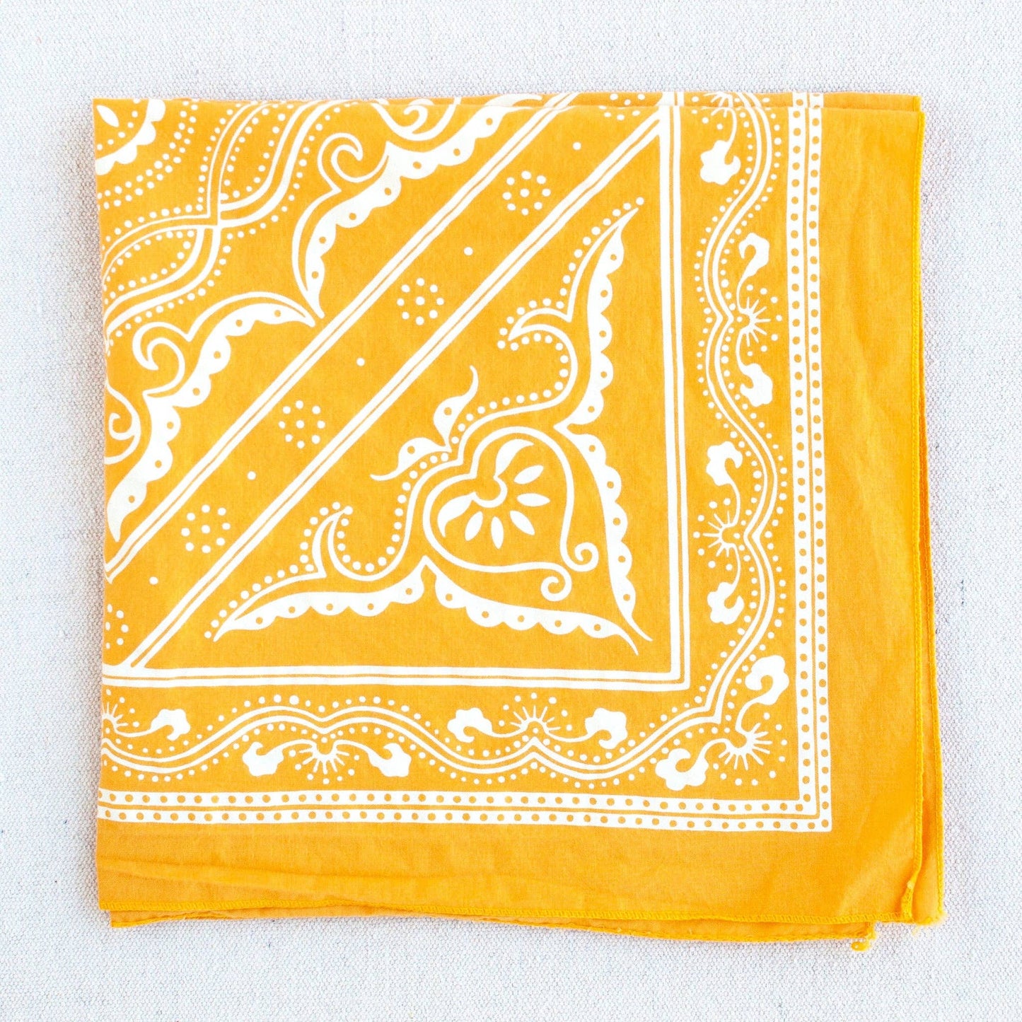 Yellow bandana with white paisley pattern on a light gray background