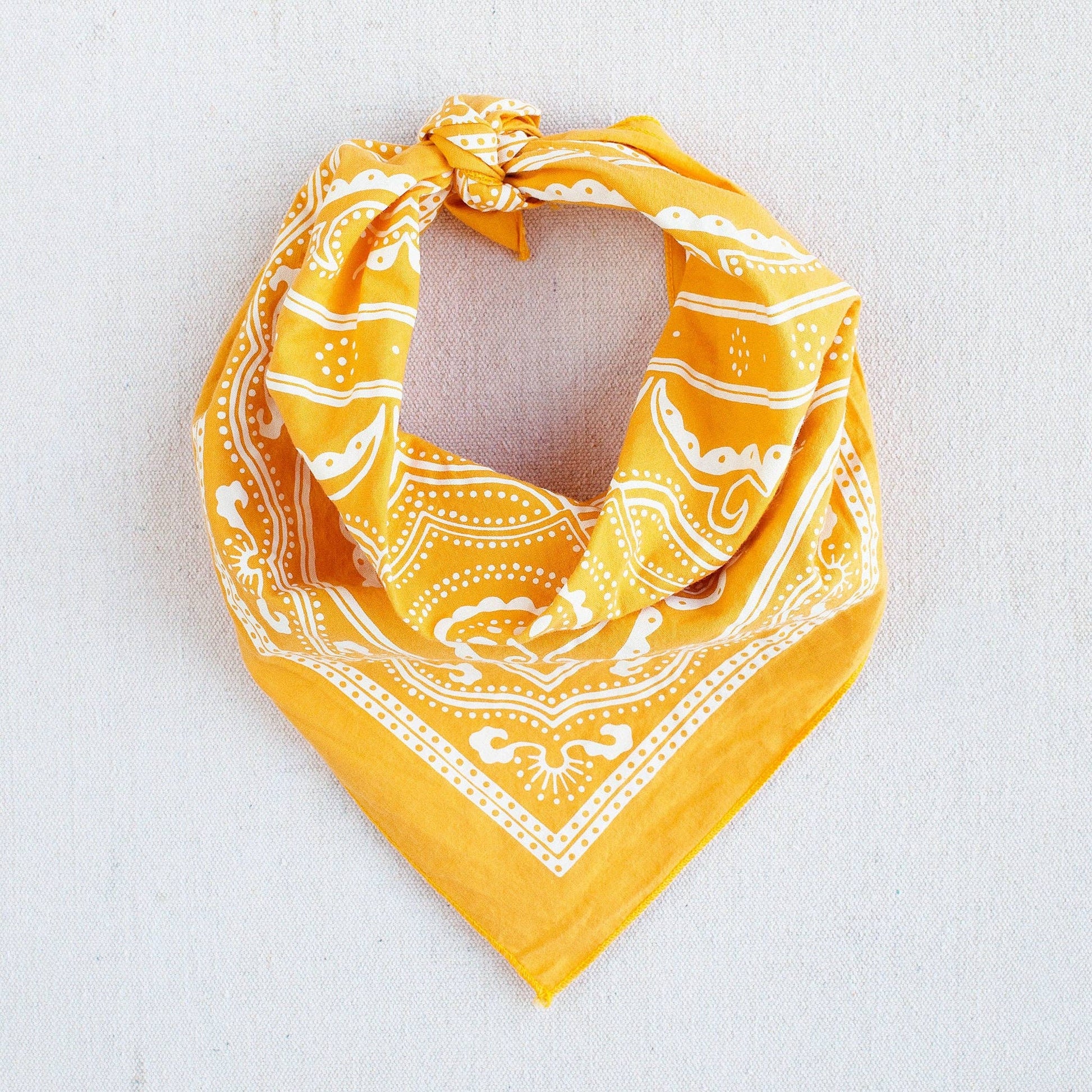 Yellow bandana with white patterns on a light gray background