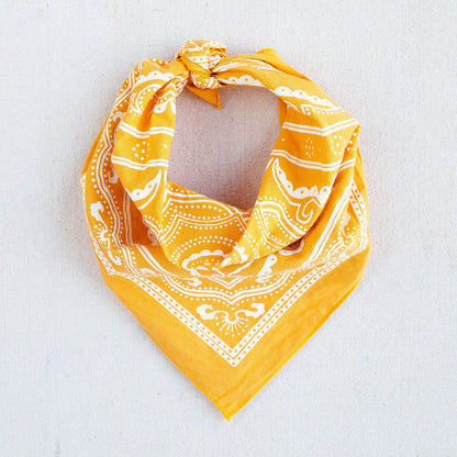 Yellow bandana with white patterns on a light gray background