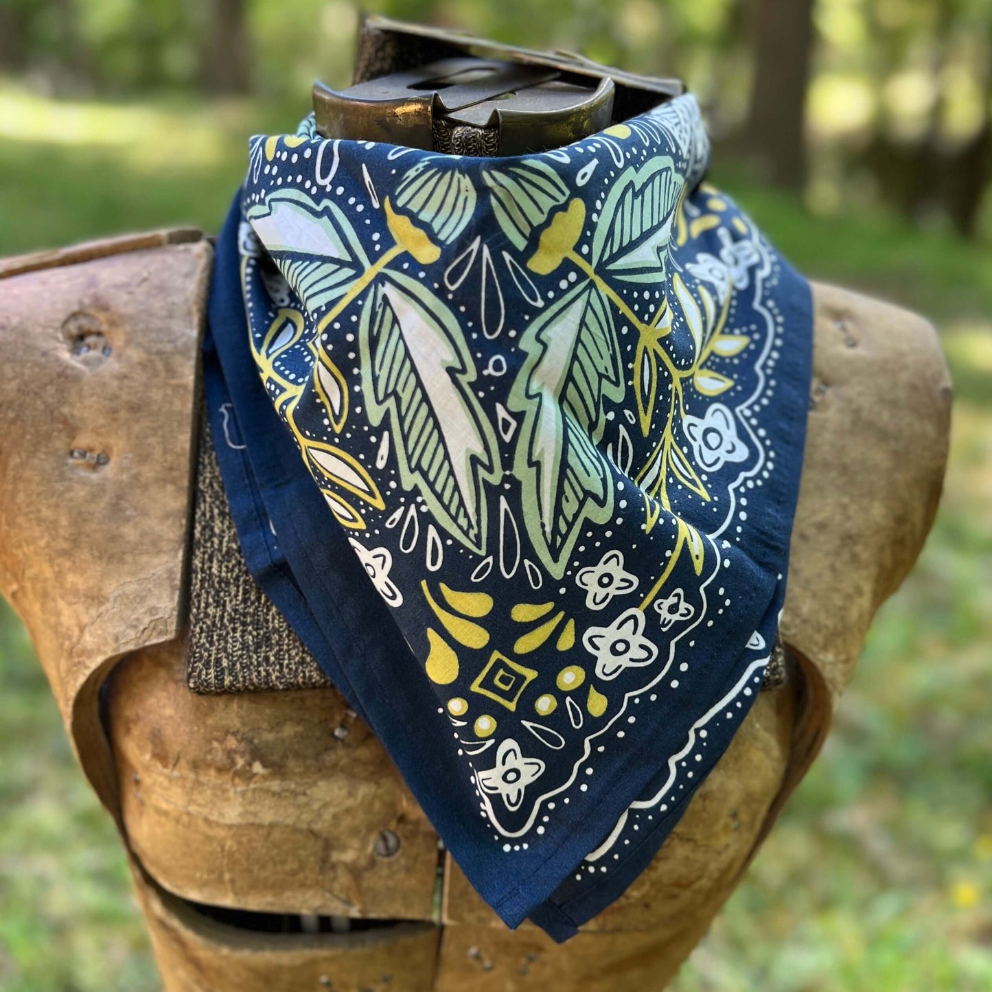 Navy blue bandana with green and yellow patterns draped over a wooden object outdoors.