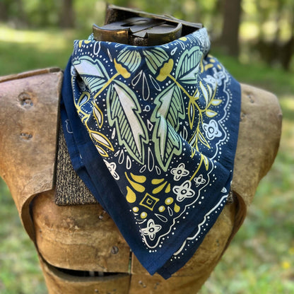 Navy blue bandana with green and yellow patterns draped over a wooden object outdoors.