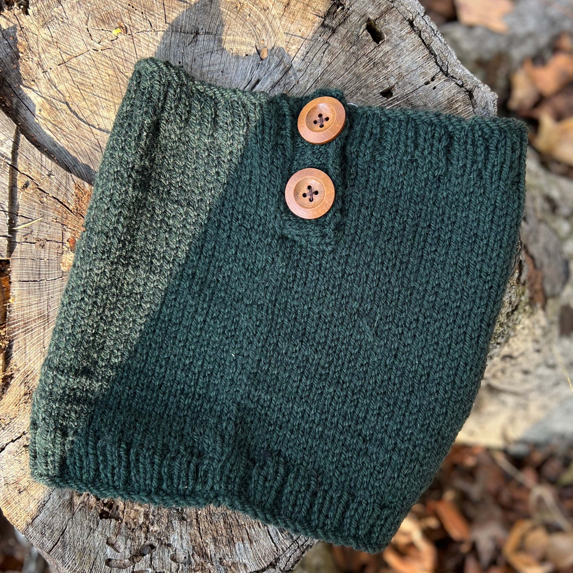 Green knitted scarf with buttons on a wooden surface
