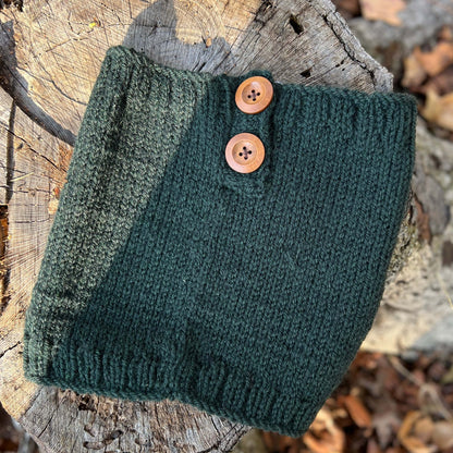 Green knitted scarf with buttons on a wooden surface