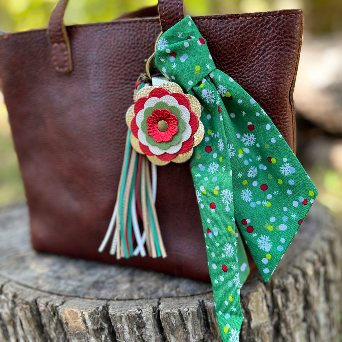 green printed purse scarf with leather flower and tassel on brown bag