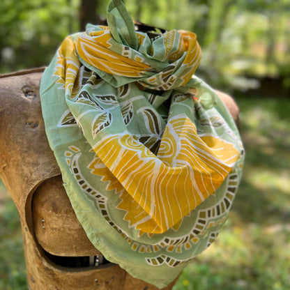 Green and yellow patterned bandana draped over a wooden surface with a blurred natural background