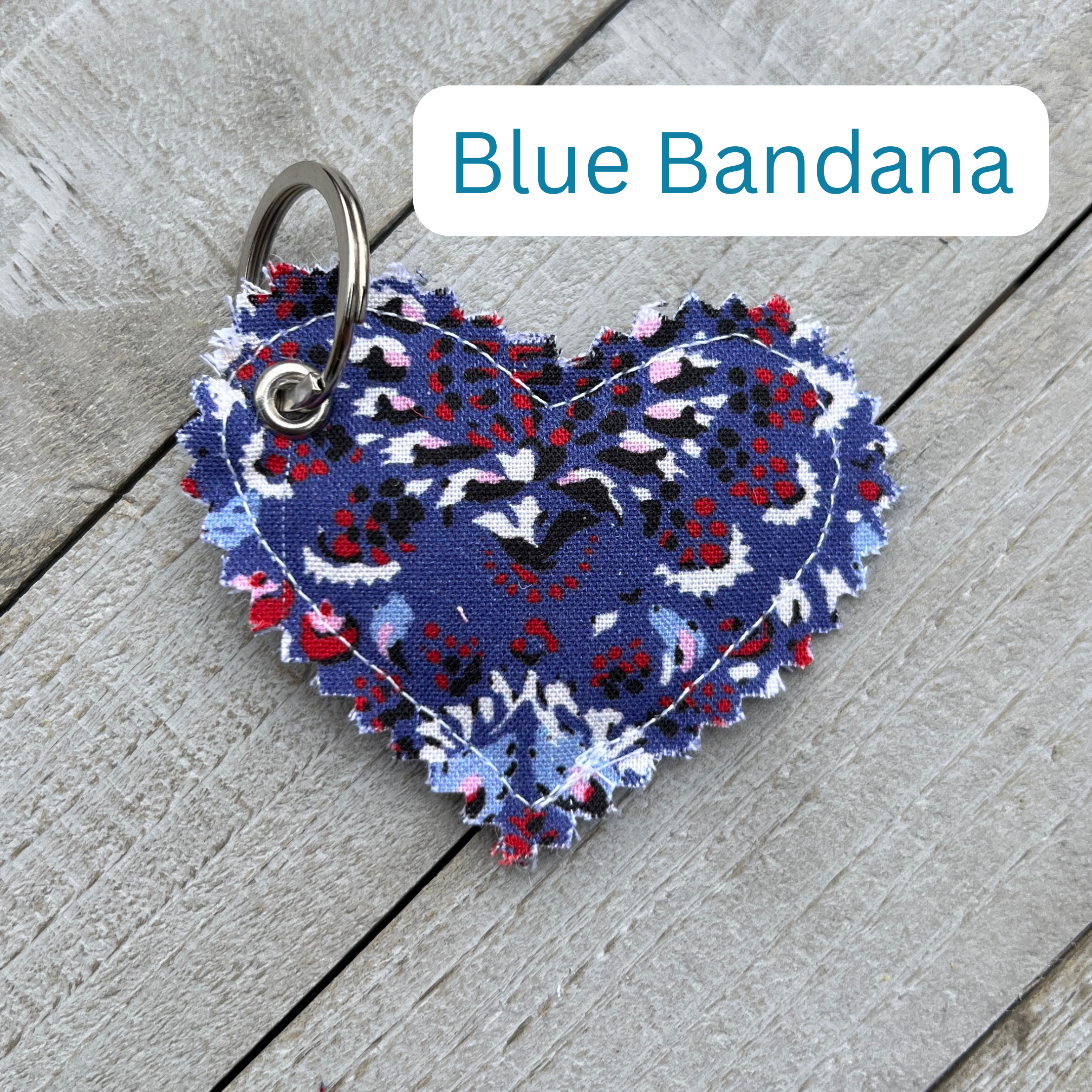 Heart-shaped blue bandana keychain on a wooden surface with 'Blue Bandana' text above.