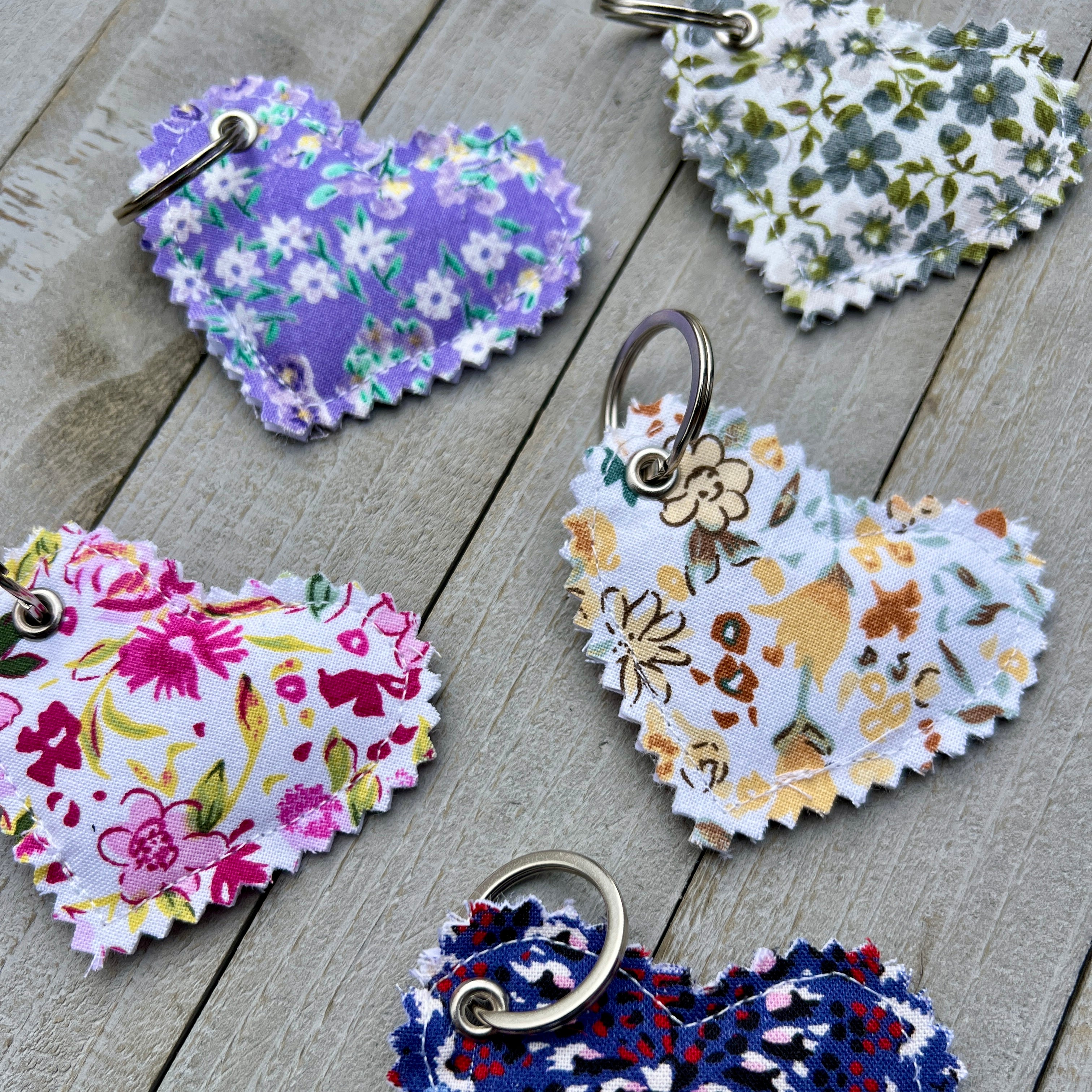 Heart-shaped floral keychains on a wooden surface